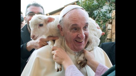 A lamb is placed around Francis' neck in January 2014 as he visits a living nativity scene staged at a church on the outskirts of Rome.