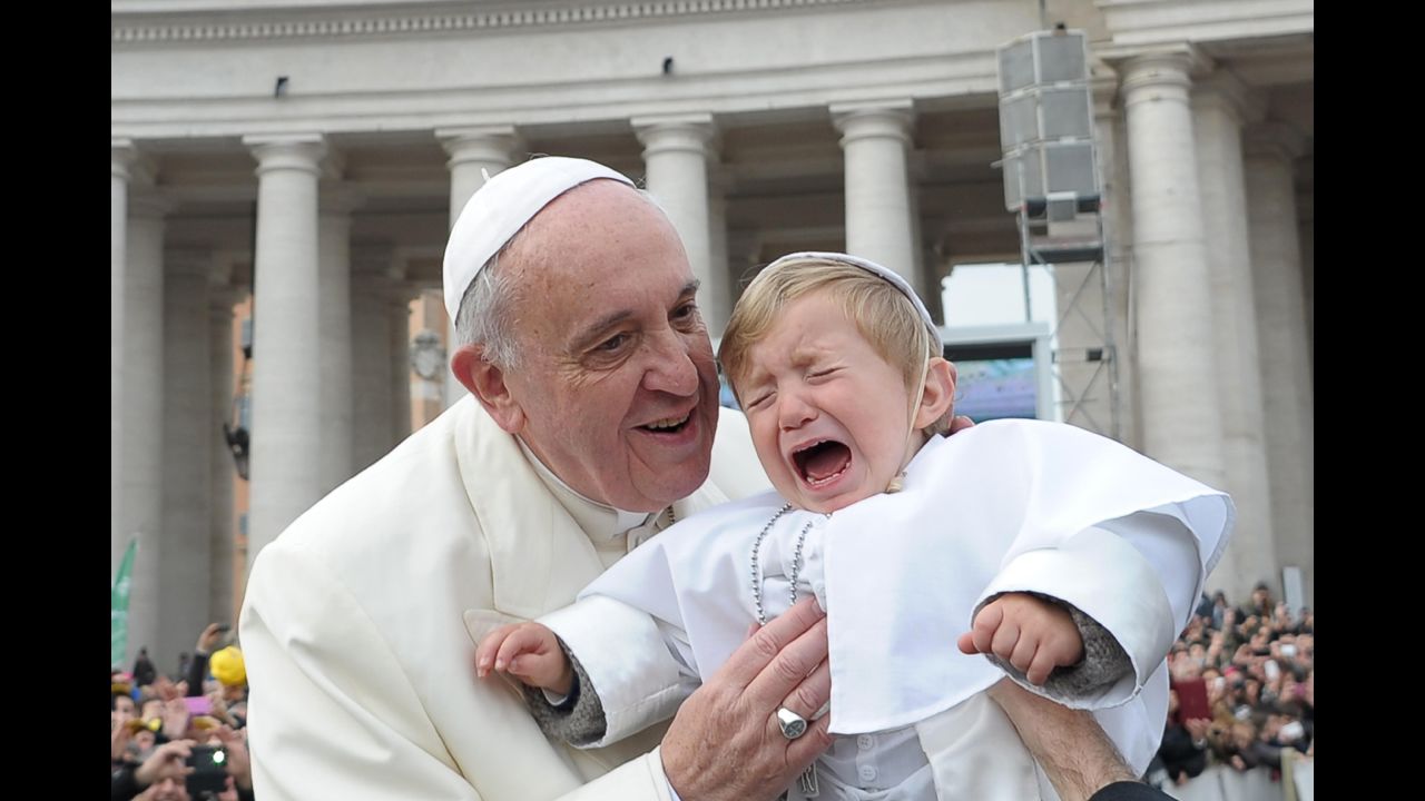 Daniele De Sanctis, a 19-month-old dressed as the pope, is handed to Francis as the pontiff is driven through the crowd in St. Peter's Square in February 2014.
