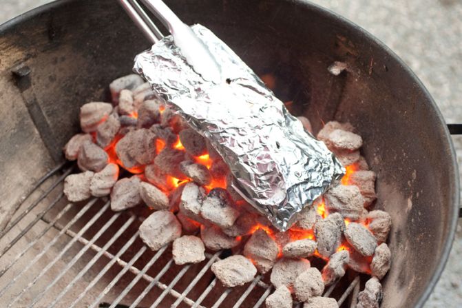 BUILD TWO-LEVEL FIRE: Pour a full chimney of charcoal briquettes in an even layer over half of the grill. Place the wood chip packet on top of the coals and let the grill heat up.<br />WHY? This setup creates a cooler side, where the brisket can cook relatively gently.<br />