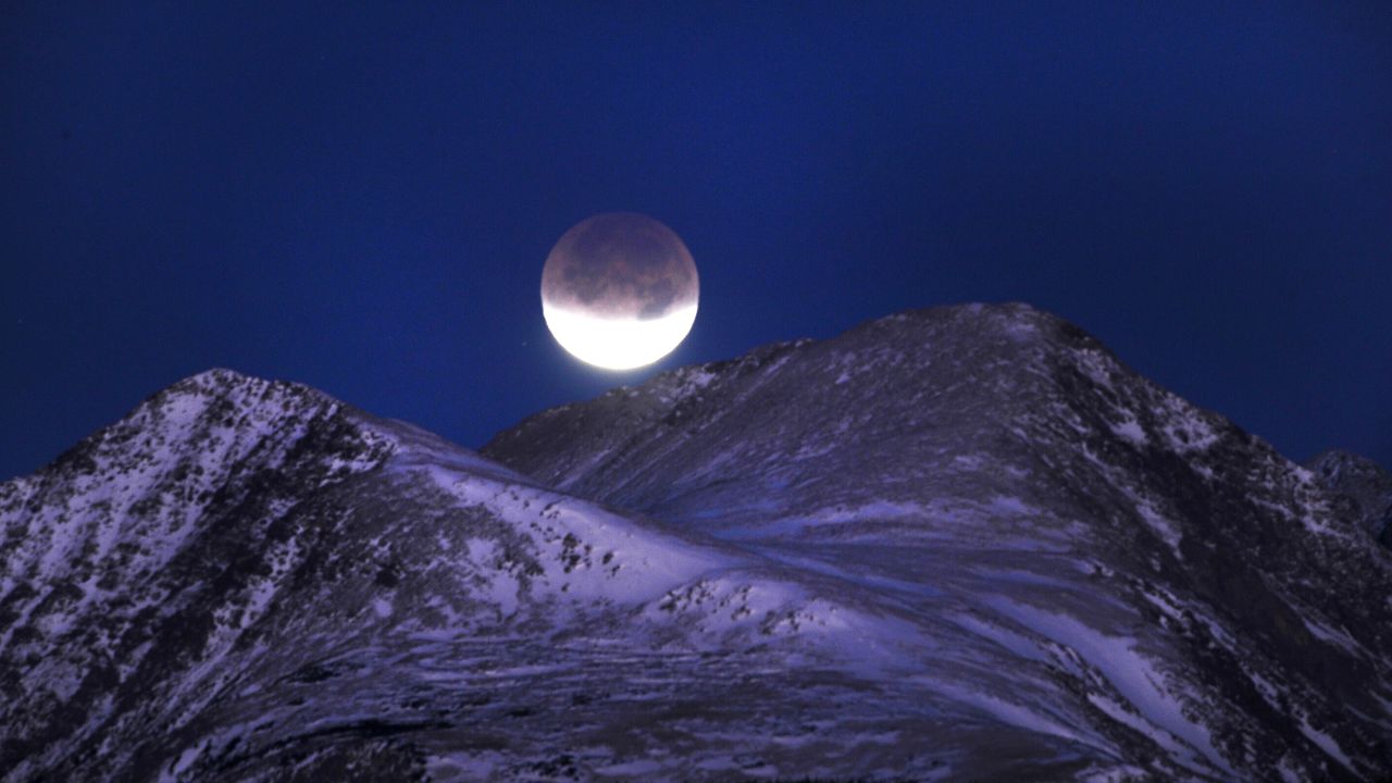 The lunar eclipse in December 2011 is almost complete before it dips behind the Indian Peaks Wilderness area near Nederland, Colorado.