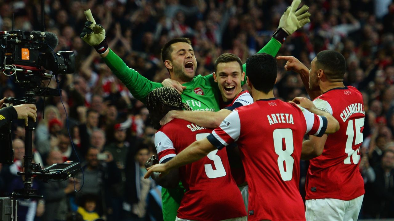 Arsenal players mob goalkeeper Lukasz Fabianski after the Gunners beat Wigan on penalties in the FA Cup. 