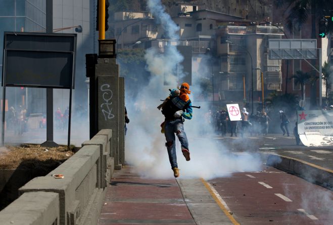 A masked anti-government demonstrator throws a tear gas canister back at National Police during clashes in Caracas on Saturday, April 12.