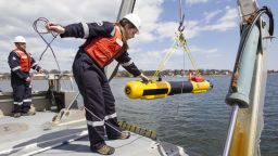 A submarine built by Bluefin Robotics is lowered into the water by systems engineer Cheryl Mierzwa in Quincy, Mass., Wednesday, April 9, 2014. Bluefin Robotics shipped a version of their submarine to help locate the missing Malaysian Airlines Flight 370, by using its side-scan sonar. (AP Photo/Scott Eisen)