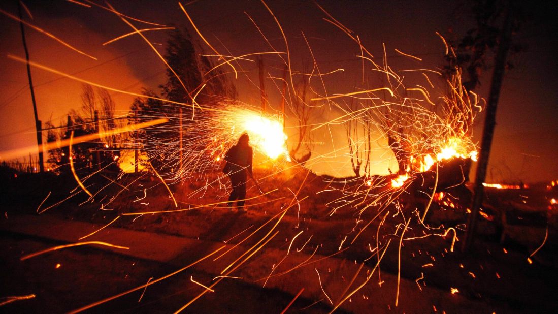 A person tries to extinguish flames as sparks fly.