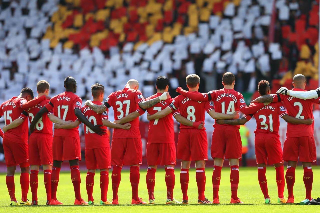 The Liverpool players link arms as they join a silence for the victims in 2014.