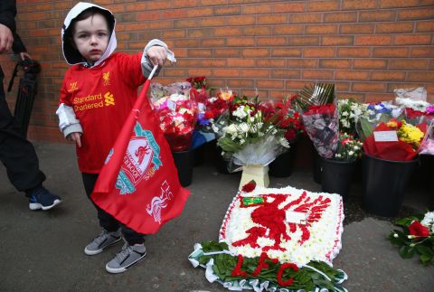 A young fan stands next to floral tributes laid in memory of the victims ahead of the Liverpool-Manchester City game at Anfield.