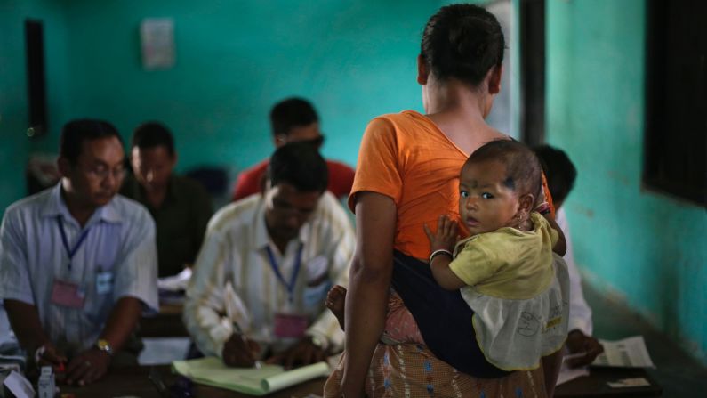 A woman carries her child and waits for her identity to be checked before voting in Diphu, India, on April 12.