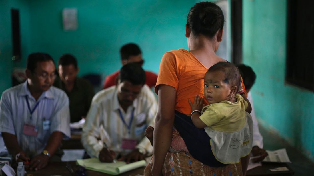 A woman carries her child and waits for her identity to be checked before voting in Diphu, India, on April 12. 
