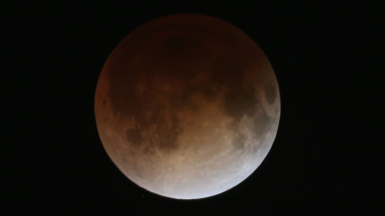 The red hue is caused by refracted sunlight in the Earth's atmosphere, which bounces off the moon while in shadow. The entire reddening process takes about an hour.