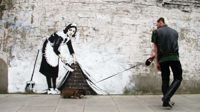 Un hombre camina al lado de una pieza de Banksy en Londres en 2006. 