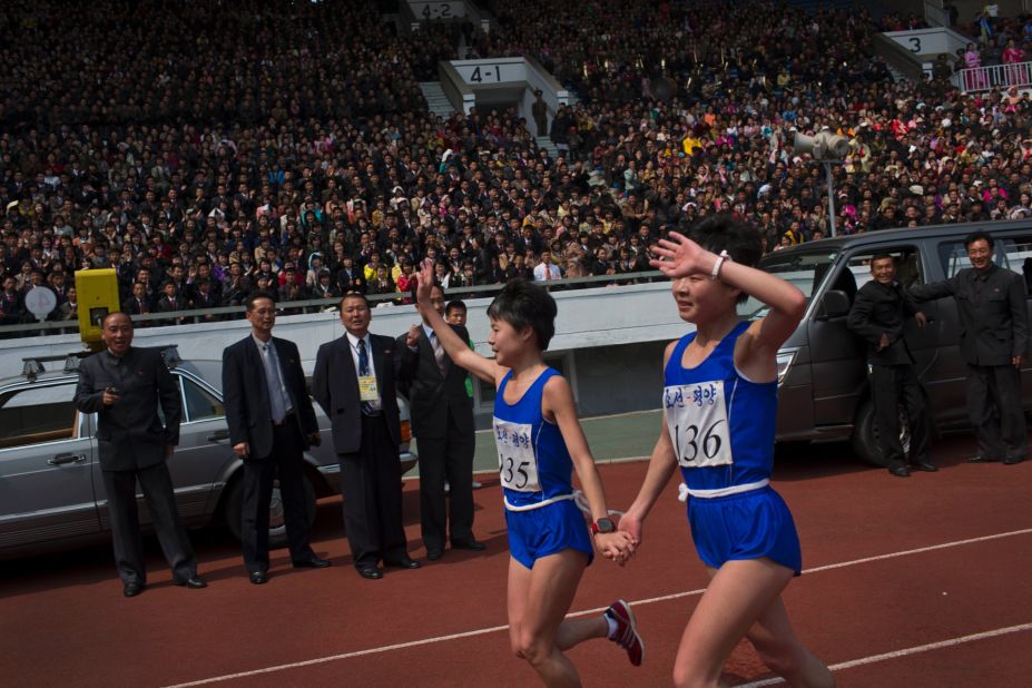 North Korean twin sisters Kim Hye Gyong (135) and Kim Hye Song (136) take a victory lap together after placing first and second respectively in the women's race.