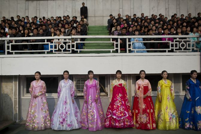 North Korean women in traditional dresses stand next to the running track inside Kim Il Sung Stadium.
