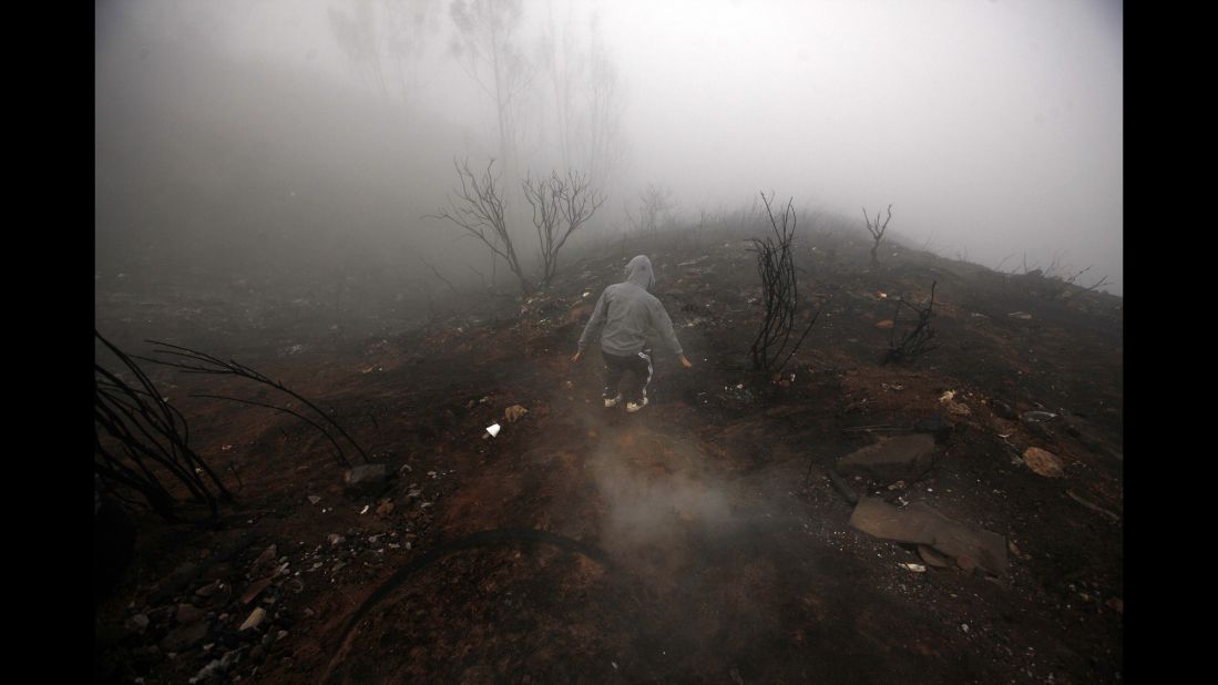 A person walks through the burnt remains of a hill Tuesday, April 15, after a wildfire burned through areas of Valparaiso, Chile. Authorities say the fire in Valparaiso and the suburb of Vina del Mar destroyed hundreds of homes, claimed several lives and forced thousands to evacuate.