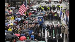 Survivors, officials, first responders and guests pause as the flag is raised at the finish line during a tribute in honor of the one year anniversary of the Boston Marathon bombings, Tuesday, April 15, 2014 in Boston. (AP Photo/Charles Krupa)
