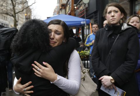 Olivia Savarino, facing the camera, hugs Christelle Pierre-Louis during the ceremonies on Boylston Street. Savarino was working at the Forum restaurant when a bomb went off in front of the building on April 15, 2013.