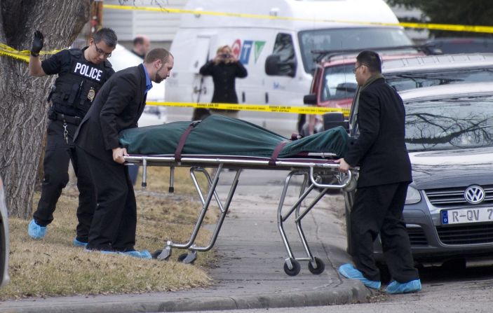 Police remove a body from the scene of a multiple fatal stabbing  in northwest Calgary, Alberta.