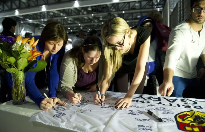 University of Calgary students and staff sign condolences on a banner during a memorial service for victims.