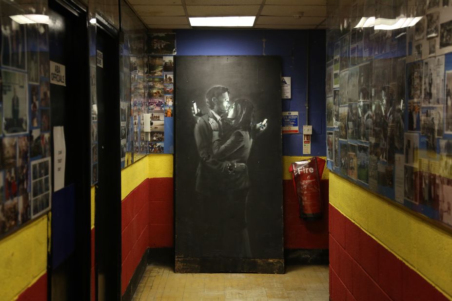 The artist has also taken on lighter themes: Banksy's Mobile Lovers, featuring a man and a woman embraced and looking at their mobile phones, sprayed onto a black wooden board is displayed inside the Broad Plain & Riverside Youth Project on April 16, 2014 in Bristol, England. 