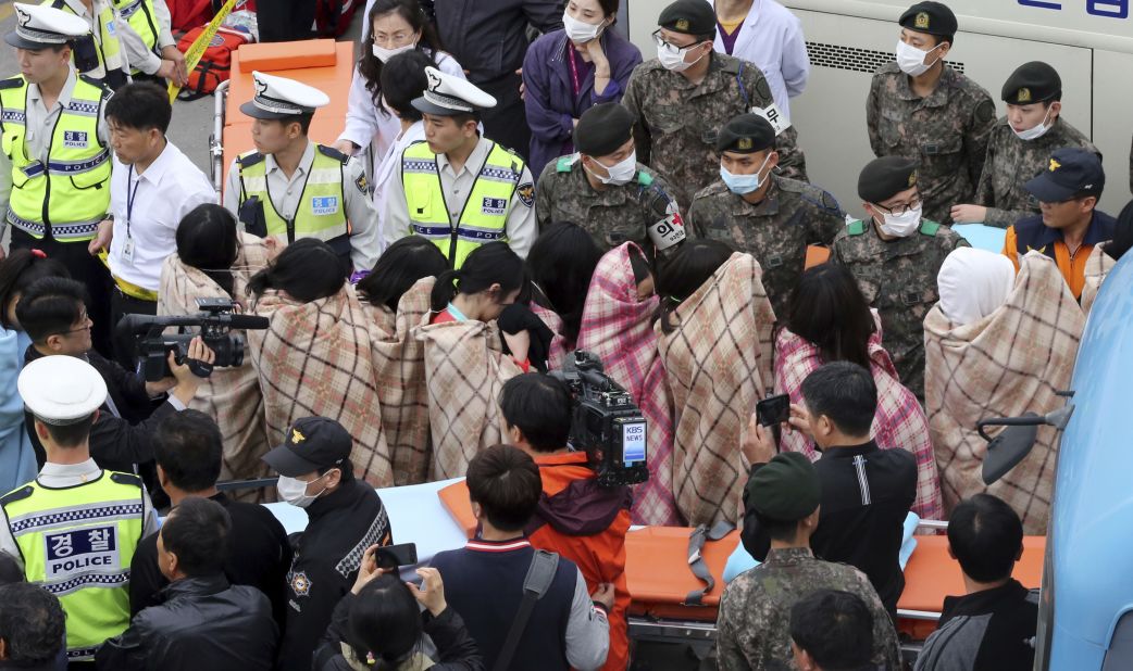 Officials escort rescued passengers April 16 in Jindo.