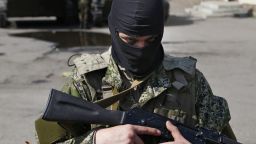 A masked gunman guards combat vehicles with Russian, Donetsk Republic and Ukrainian paratroopers, flags and gunmen on top, parked in downtown of Slovyansk on Wednesday, April 16, 2014.