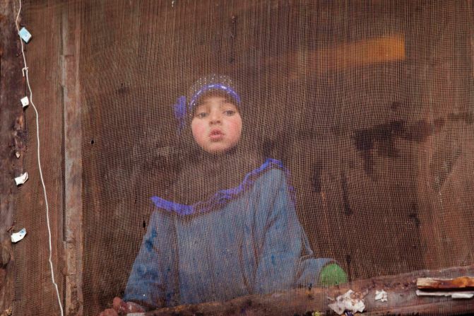 A young girl watches an election campaign rally from her house in Rawalpora, India, on April 15.