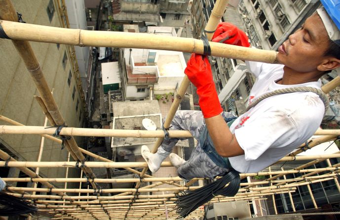 Bamboo scaffolders, perched precariously on bits of bamboo suspended in mid-air while attached to a small harness, are a common sight on Hong Kong's streets.