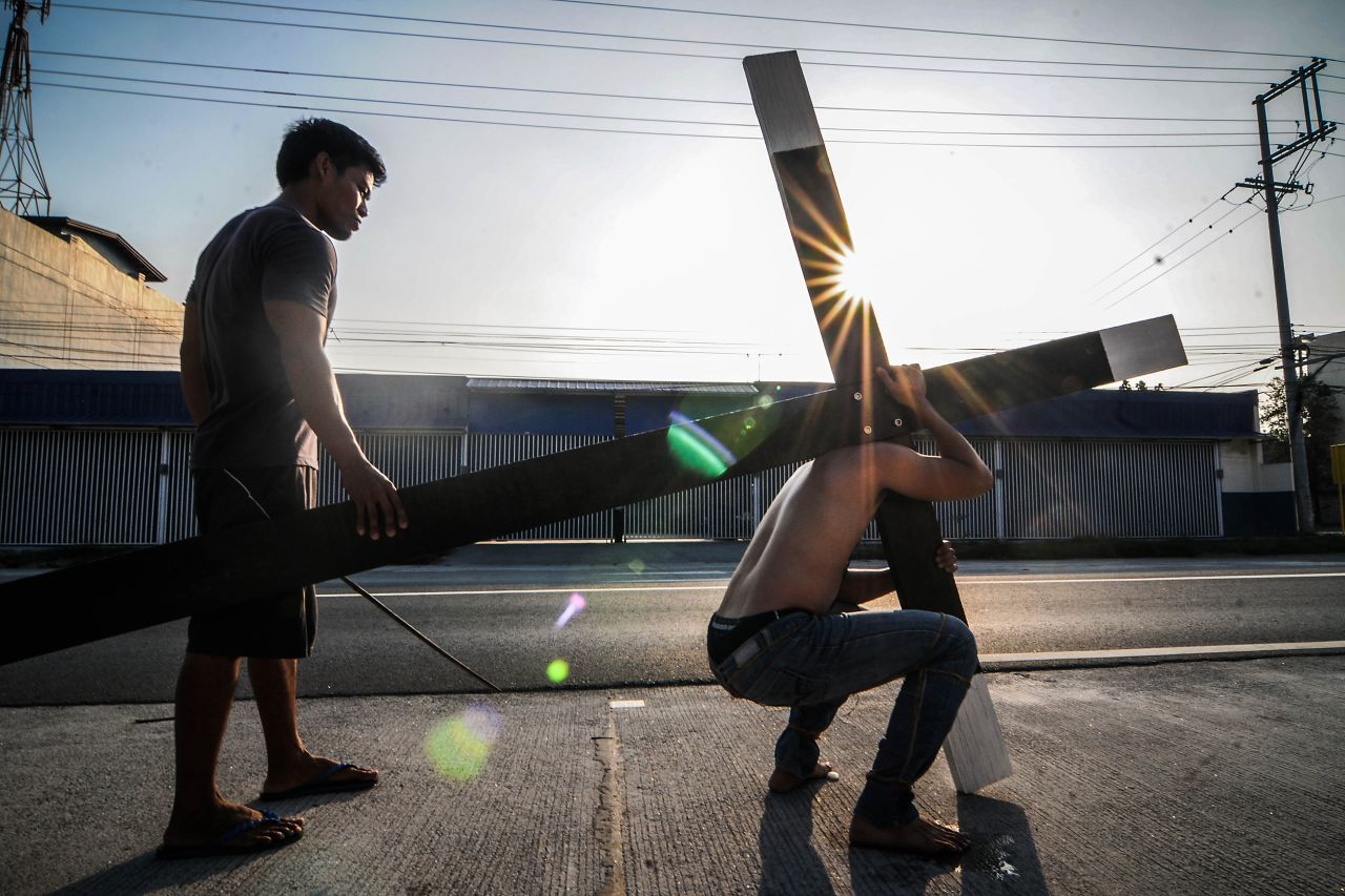 A Filipino carries a wooden cross along a road on Maundy Thursday in San Fernando, Pampanga province, Philippines, on April 17.