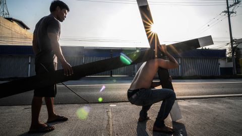 A Filipino carries a wooden cross along a road on Maundy Thursday in San Fernando, Pampanga province, Philippines, on April 17.
