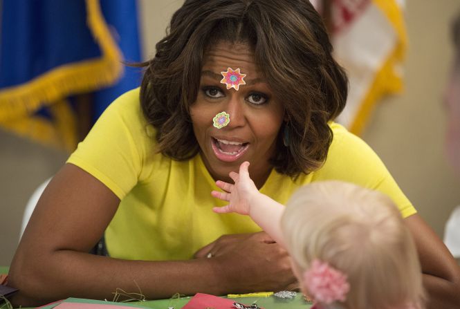 Michelle Obama, the first lady of the United States, has stickers put on her face by 20-month-old Lily Oppelt on Monday, April 14, during Obama's visit to the Fisher House at the Walter Reed Army Medical Center in Bethesda, Maryland. The Fisher House Foundation provides housing to military families while a loved one receives treatment at a nearby medical facility.