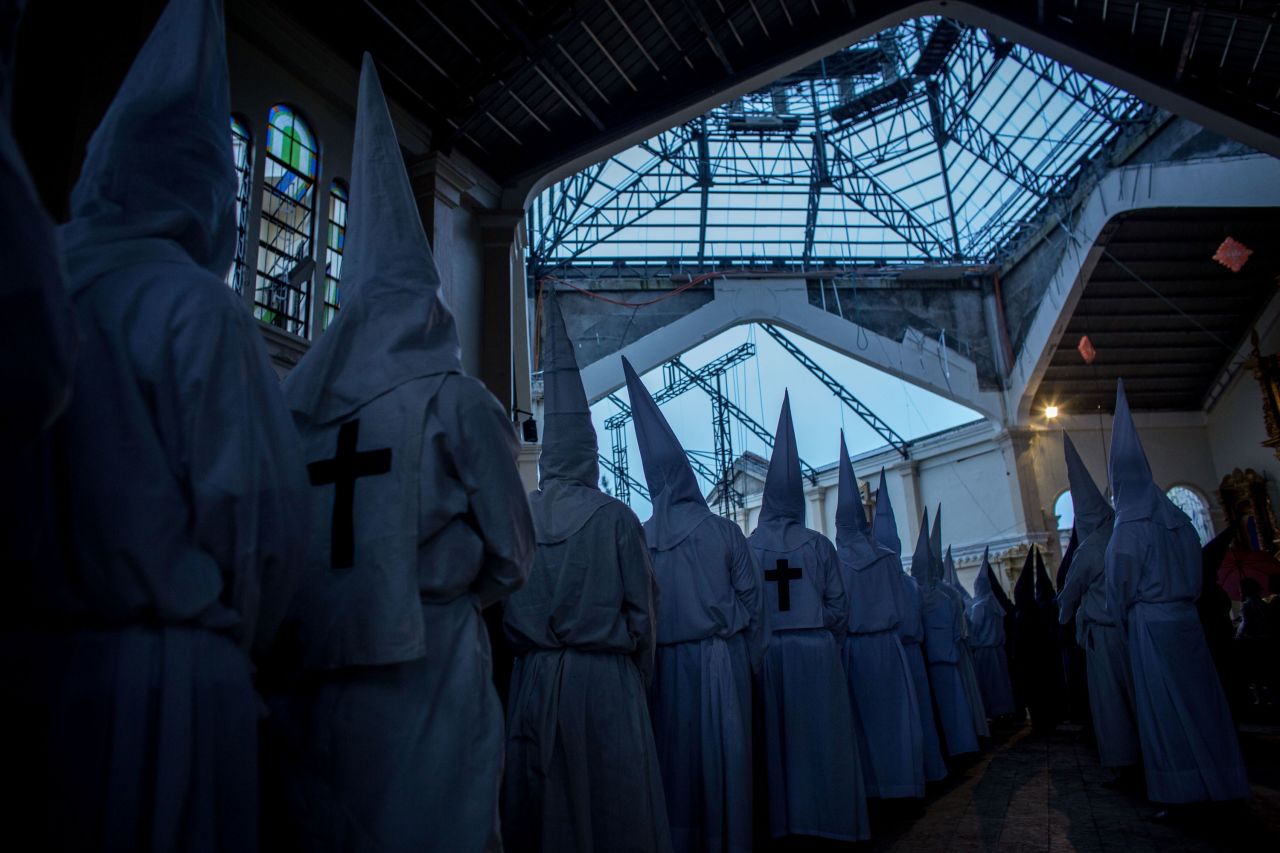 Penitents watch on from a damaged part of the Palo Cathedral during the Maundy Thursday Mass at Palo Cathedral in Palo, Leyte, Philippines, on April 17.