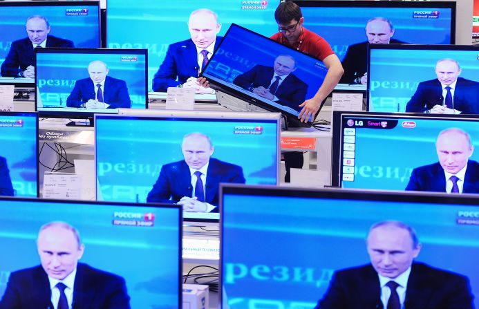 A shop assistant in Moscow moves a television screen Thursday, April 17, during the annual question-and-answer session held by Russian President Vladimir Putin. 