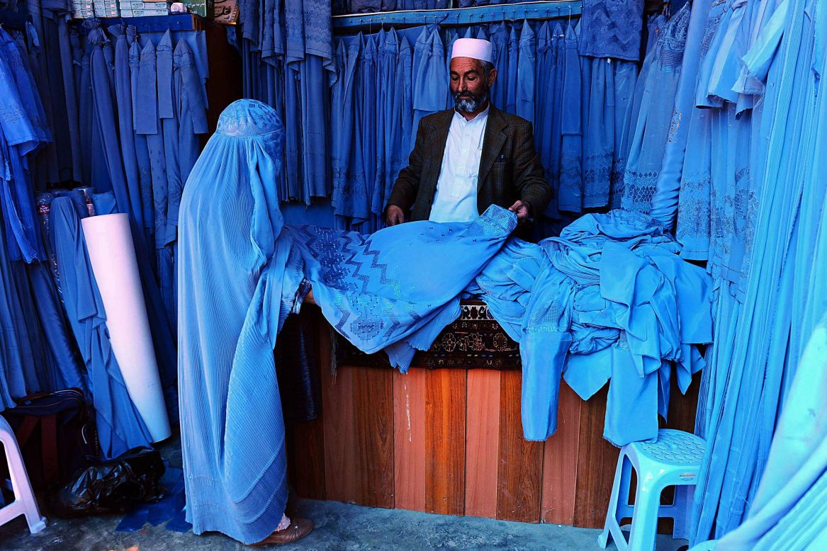 An Afghan shopkeeper shows a burqa to a customer in Herat, Afghanistan, on Sunday, April 13.