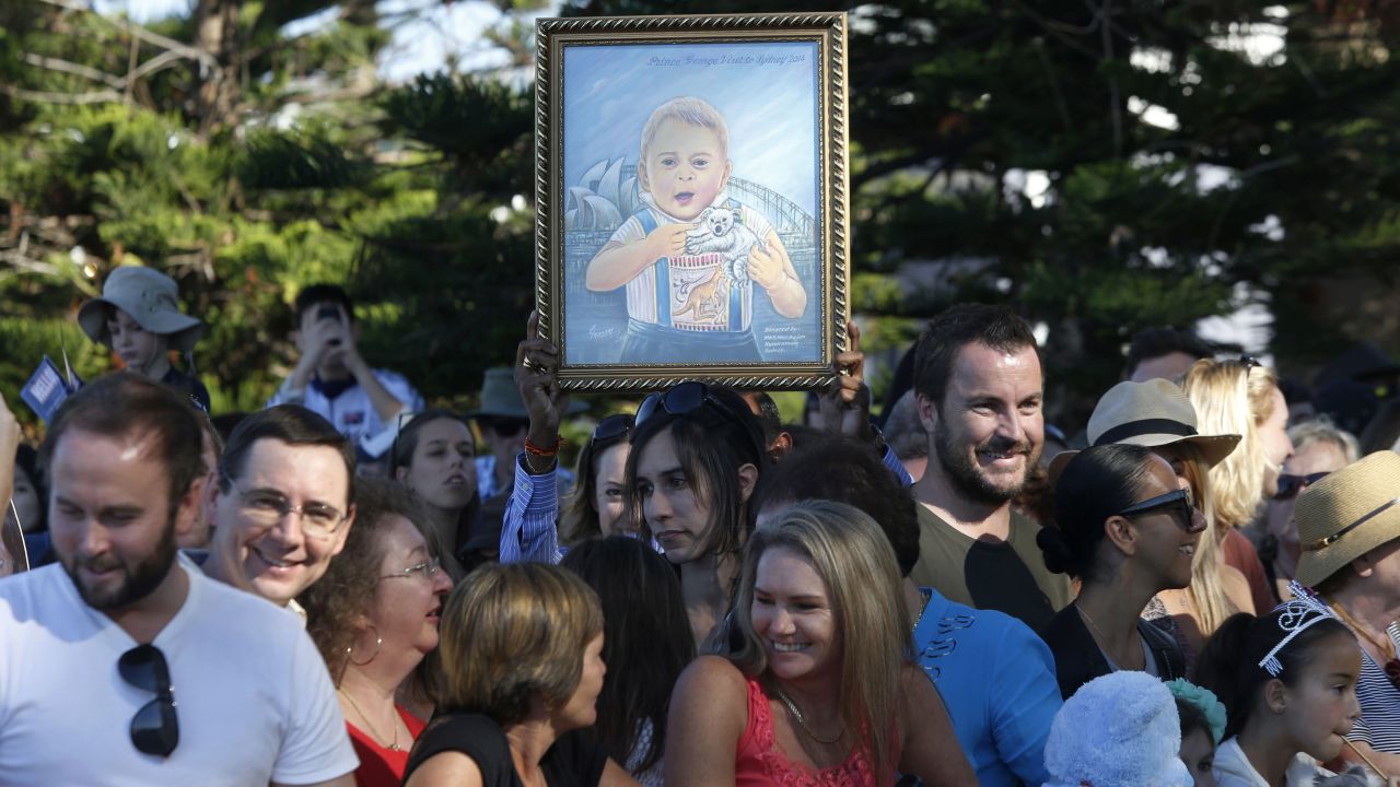 A woman holds up a painting of Prince George before the royal couple's visit to Manly Beach.