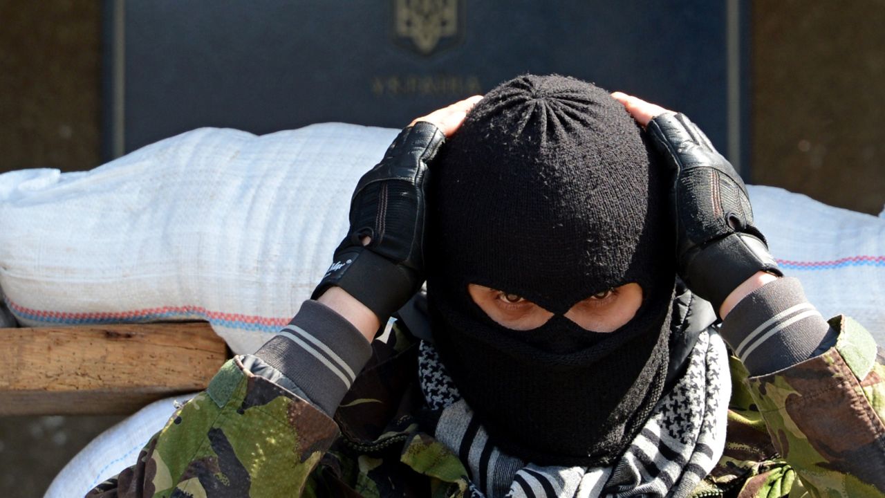 A masked man stands guard outside a regional administration building seized by pro-Russian separatists in Slovyansk on Friday, April 18. 