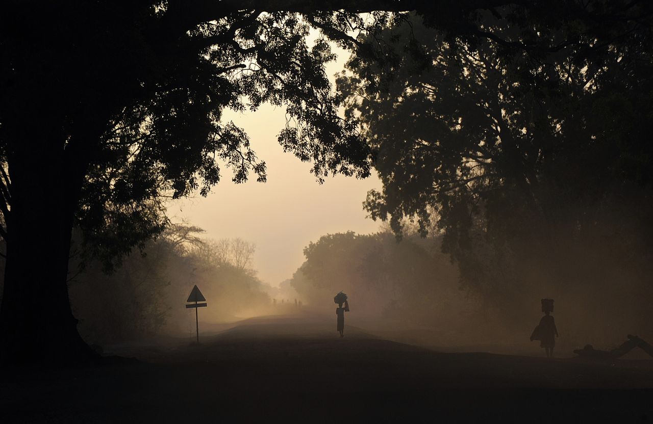 People are silhouetted at dawn on Thursday, February 20, as they walk on the main road to Cueibet, South Sudan. 