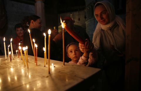 Christian worshippers light candles during Easter Sunday Mass in the Church of Holy Sepulchre in Jerusalem's Old City.