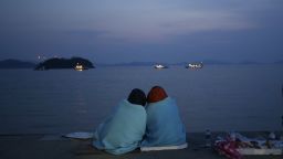 Relatives of passengers aboard the sunken ferry Sewol sit near the sea at a port in Jindo, south of Seoul, South Korea, Sunday, April 20, 2014. After more than three days of frustration and failure, divers on Sunday finally found a way into the submerged ferry off South Korea's southern shore, discovering more than a dozen bodies inside the ship and pushing the confirmed death toll to over four dozens, officials said. (AP Photo/Lee Jin-man)