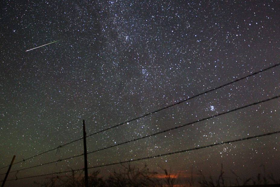 A meteor streaks past the faint band of the Milky Way galaxy above the Wyoming countryside during the 2013 Perseid meteor shower. The show happens each summer when Earth rotates through debris from the Swift-Tuttle comet. 