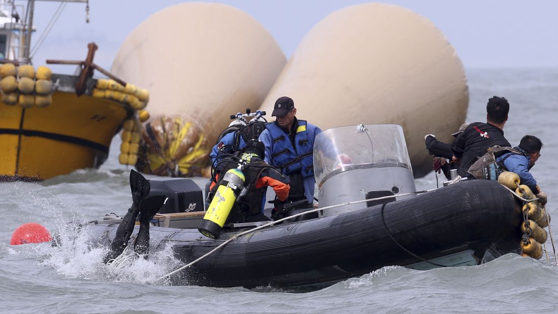 Divers jump into the water on April 21 to search for passengers near the buoys that mark the site of the sunken ferry.