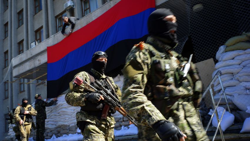 A pro-Russia activist hangs a flag of the so-called 'People's Republic of Donetsk' on the regional administration building seized by separatists as armed men in military fatigues guard the premises in the eastern Ukrainian city of Slavyansk on April 21, 2014.