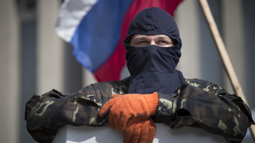 A masked pro-Russia guards barricades as the Russian national flag flies at the Ukrainian regional office of the Security Service in Luhansk, Ukraine, Monday, April 21, 2014.