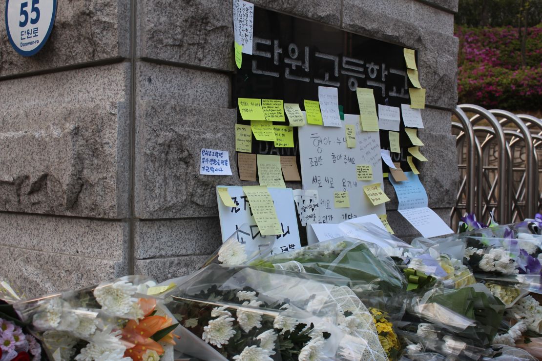 Post-it notes pile up in front of the sign at the gate of Danwon High School in Ansan, South Korea.
