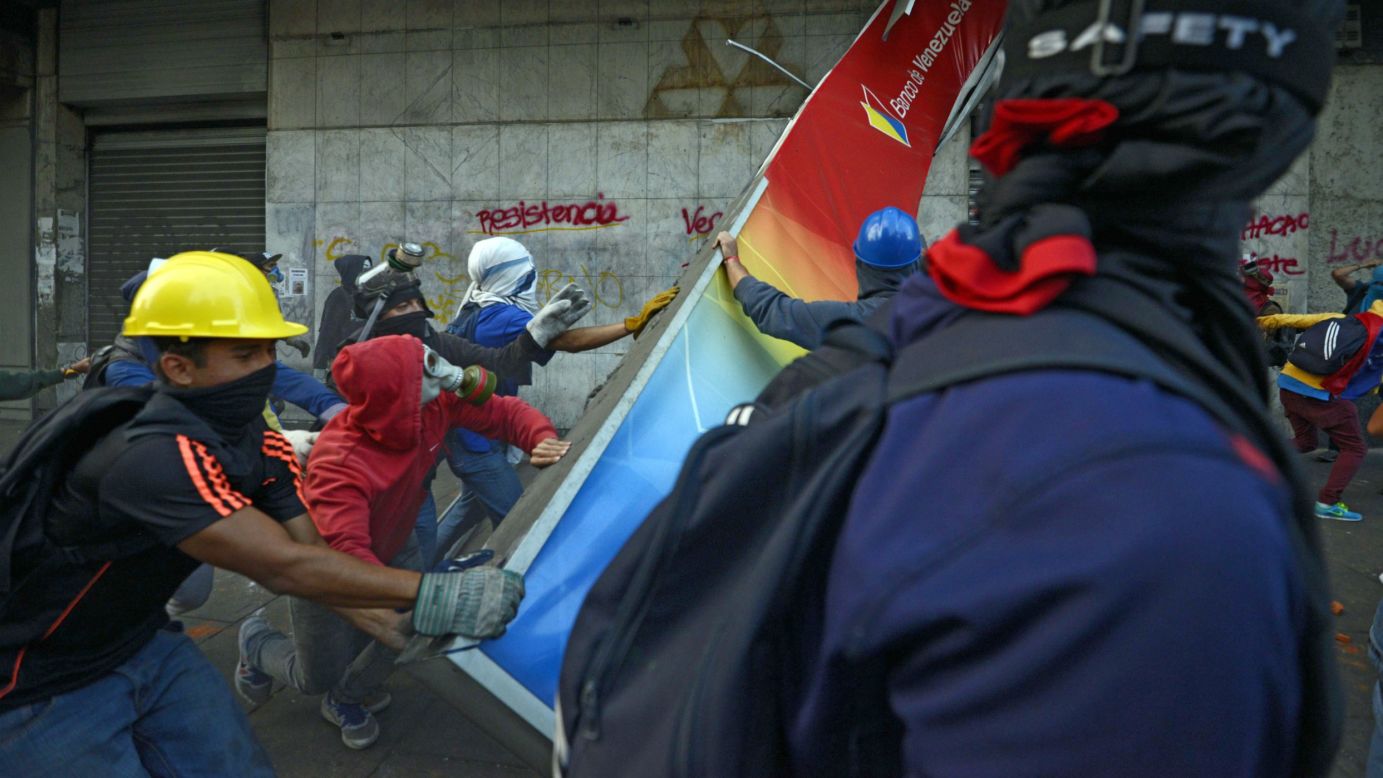 Demonstrators destroy a bank sign in Caracas during a protest against the government on Sunday, April 20.