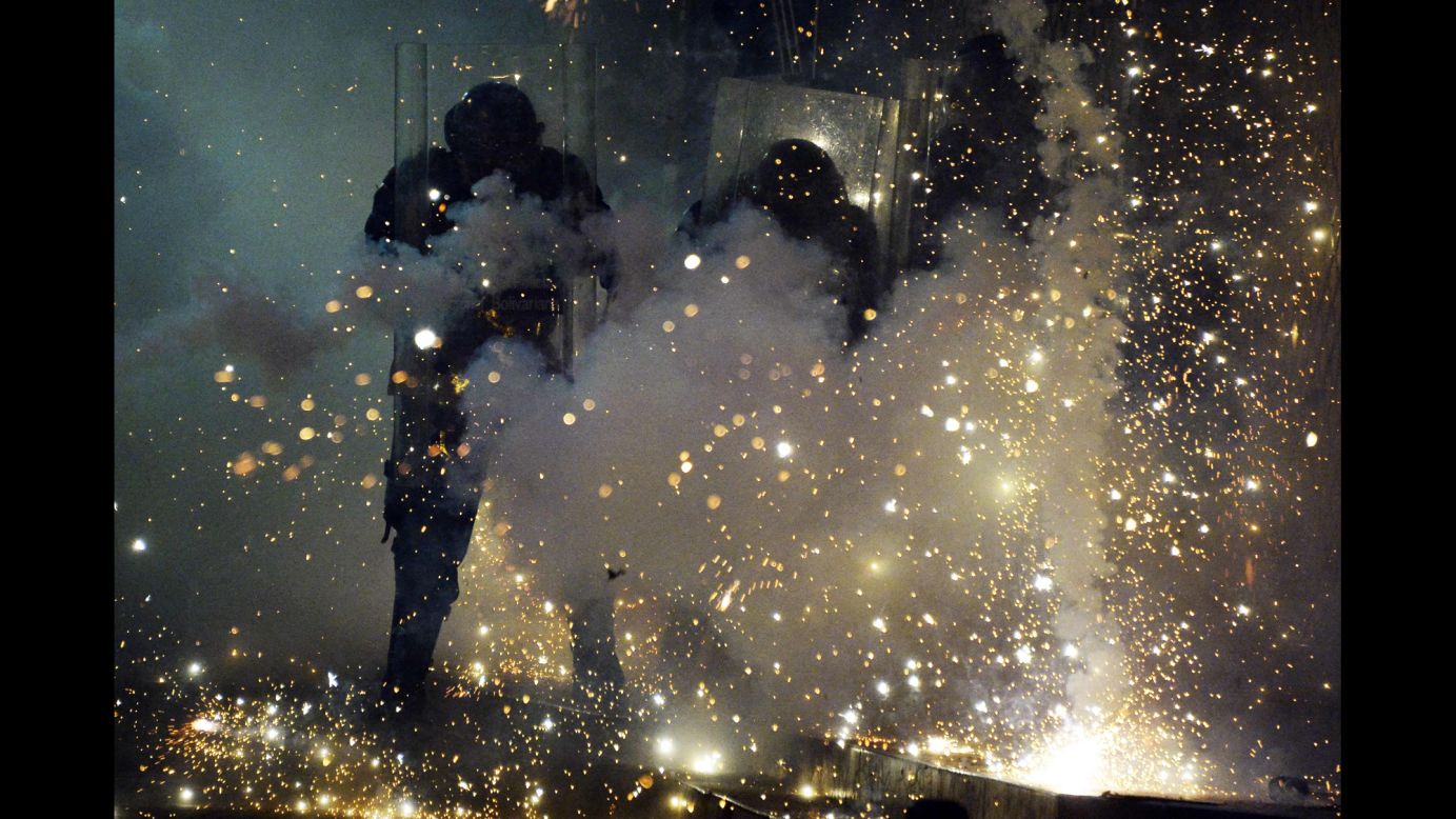 Police officers shield themselves from fireworks thrown by protesters in Caracas on April 20.