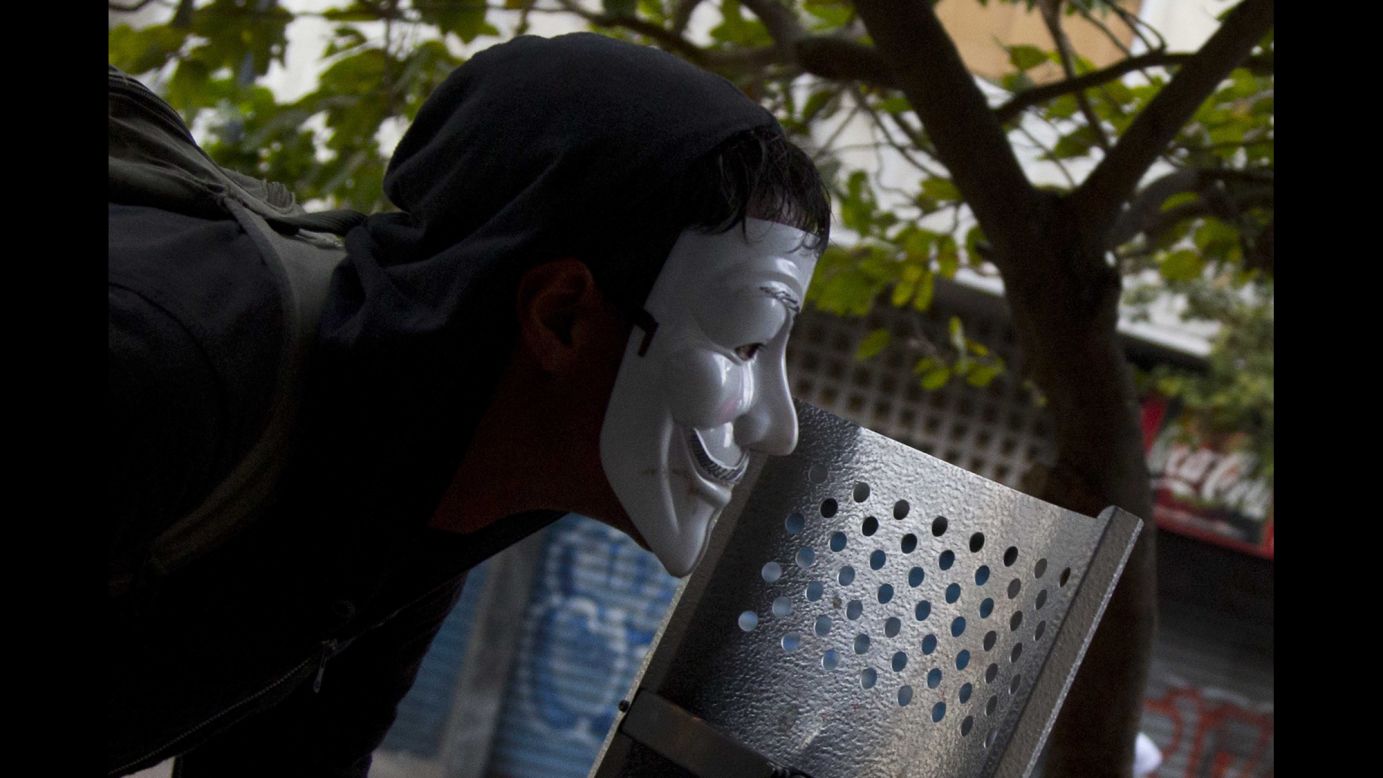 A masked protester watches clashes with the National Police in Caracas on Thursday, April 17.
