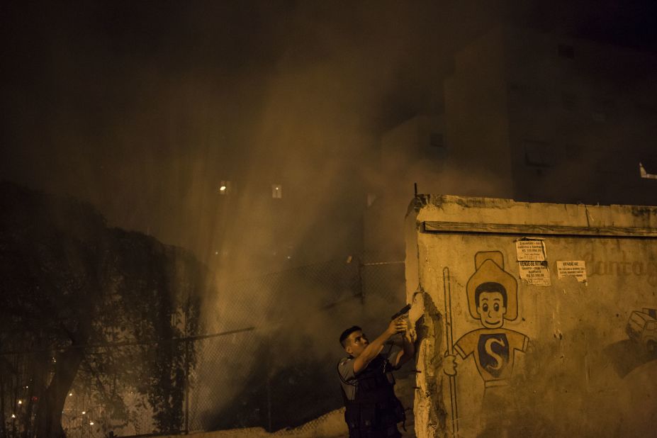 A police officer patrols the area among the smoke from burning barricades.