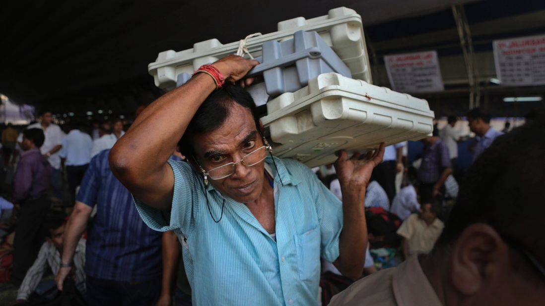 A polling official carries electronic voting machines at a distribution center in Gauhati, India, on Wednesday, April 23.