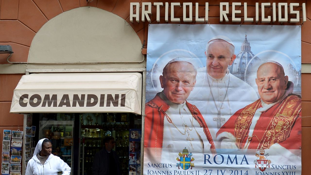 Poster showing Pope John Paul II (left) and Pope John XXIII (right), who are to be canonized by Pope Francis (center) on April 27, 2014.