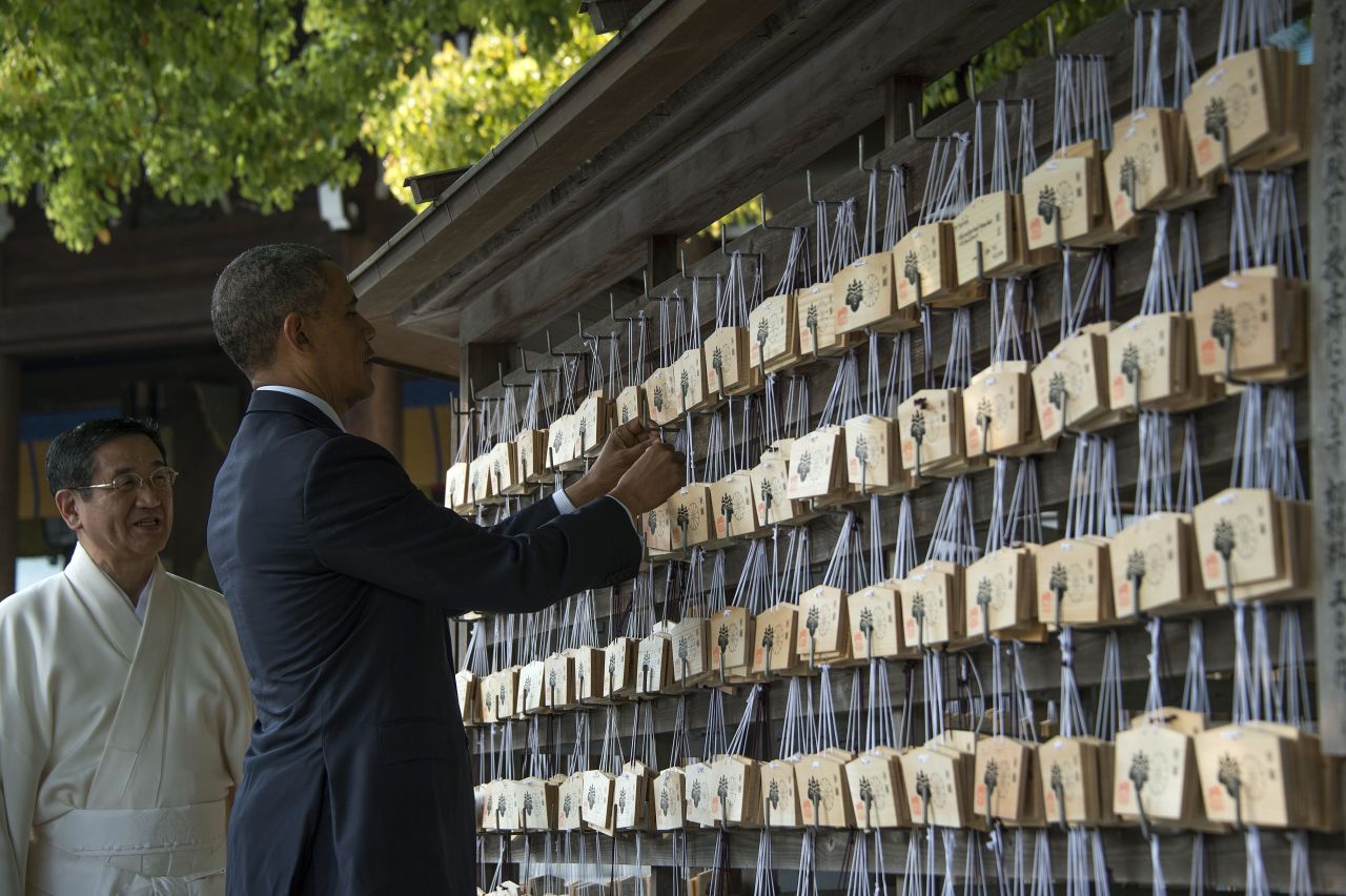 Obama places a prayer tablet on the Votive Tree at the Meiji Shrine.