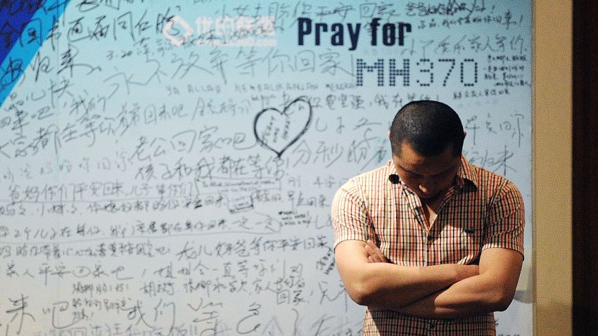 A man stands in front of a billboard in support of missing Malaysia Airlines flight MH370 as Chinese relatives of passengers on the missing Malaysia Airlines flight MH370 have a meeting at the Metro Park Hotel in Beijing on April 23.